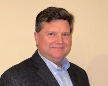 Professional headshot of a business executive in dark blazer and light blue shirt, suitable for food service industry leadership and B2B foodservice company profiles.