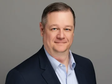 Professional headshot of a business executive in navy blazer and blue shirt, suitable for food supply and wholesale distribution industry.