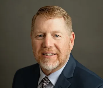 Professional headshot of a business executive in formal attire, suitable for food service and wholesale distribution industry leadership roles.